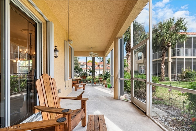 sunroom with ceiling fan with notable chandelier