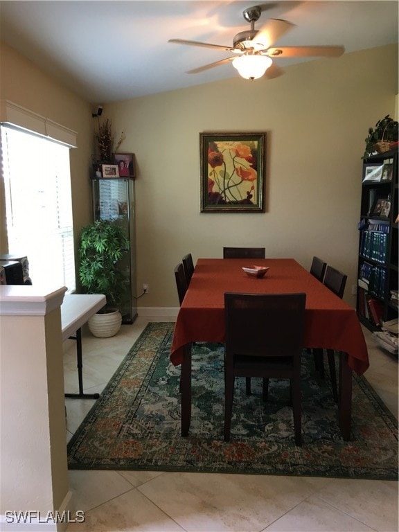 tiled dining area with ceiling fan and lofted ceiling