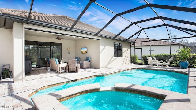 view of pool with an in ground hot tub, glass enclosure, ceiling fan, and a patio