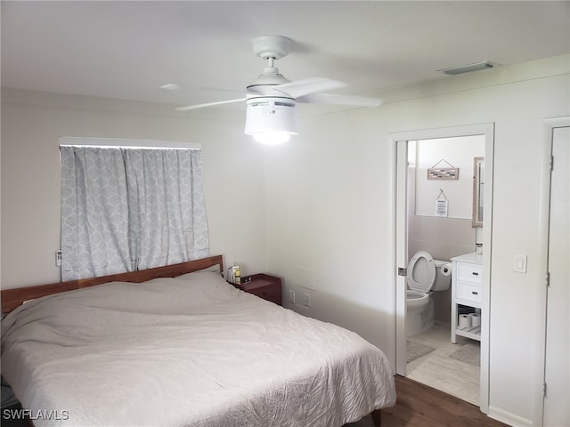 bedroom with ceiling fan, ensuite bathroom, and dark hardwood / wood-style flooring