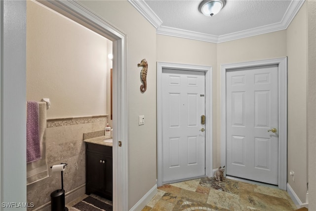 foyer featuring ornamental molding, tile walls, and a textured ceiling