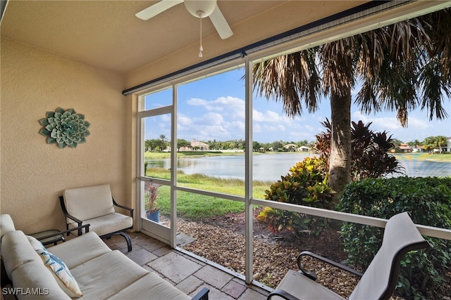 sunroom featuring ceiling fan and a water view