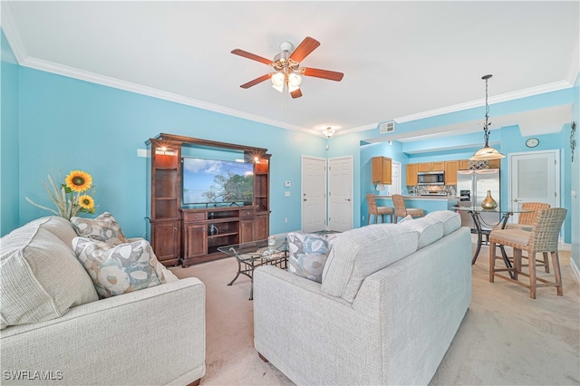 carpeted living room with ceiling fan and crown molding