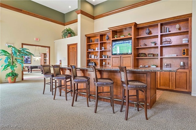 bar with a high ceiling, light colored carpet, and dark stone countertops