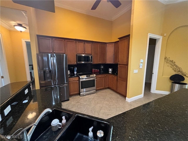 kitchen featuring appliances with stainless steel finishes, ornamental molding, dark stone counters, ceiling fan, and light tile patterned floors