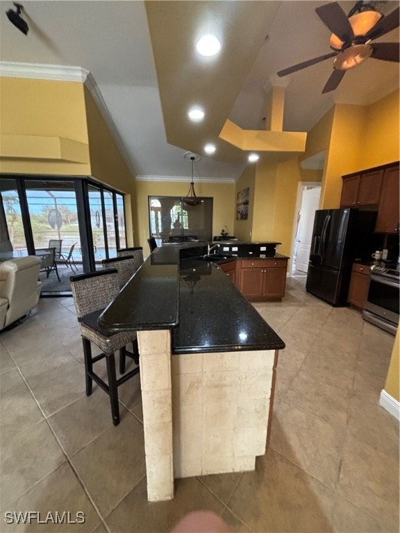 kitchen with stainless steel range oven, a kitchen bar, ceiling fan, and crown molding