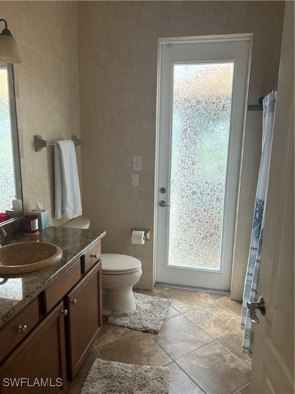 bathroom with toilet, vanity, and tile walls