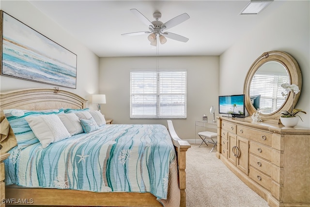 bedroom featuring ceiling fan, multiple windows, and light carpet