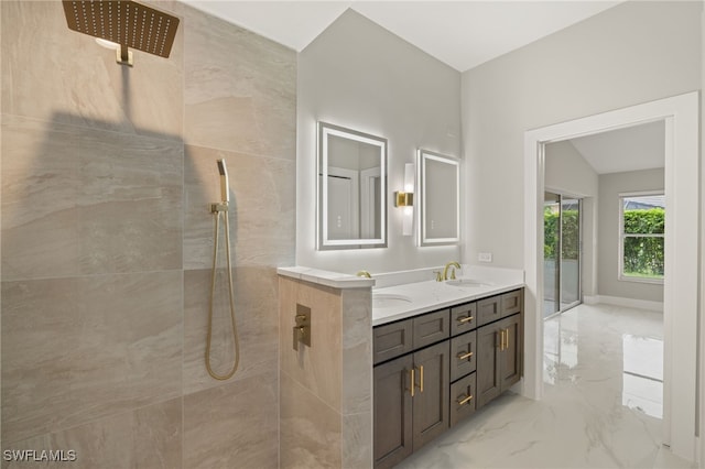 bathroom featuring vanity, a tile shower, and lofted ceiling