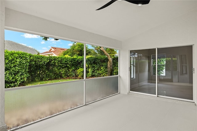 unfurnished sunroom featuring ceiling fan, a healthy amount of sunlight, and vaulted ceiling