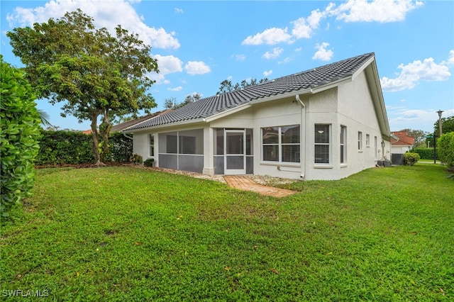 back of property with a lawn and a sunroom