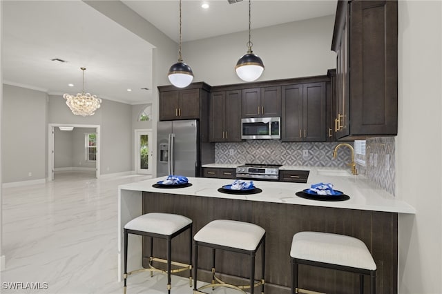 kitchen featuring kitchen peninsula, appliances with stainless steel finishes, sink, a breakfast bar area, and a chandelier