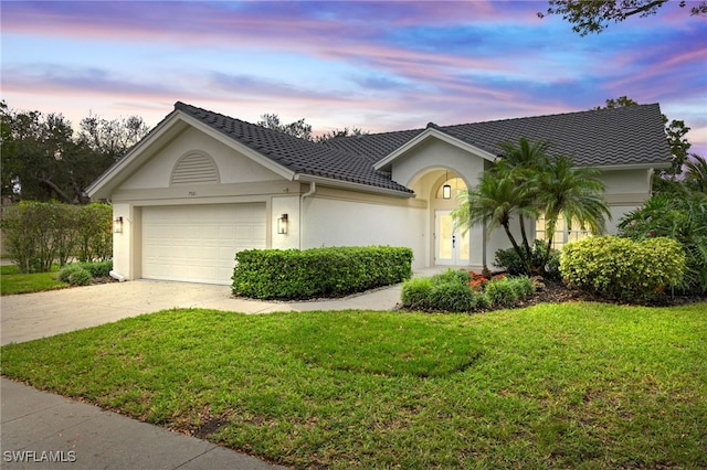 ranch-style house featuring a garage and a lawn