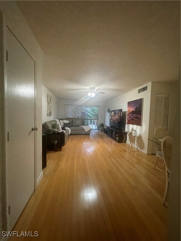 unfurnished living room with light hardwood / wood-style floors, a textured ceiling, and ceiling fan