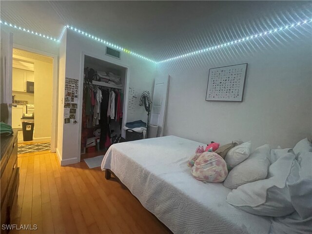 bedroom with a spacious closet, hardwood / wood-style floors, and a closet