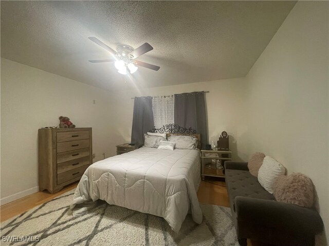 bedroom with light hardwood / wood-style flooring, a textured ceiling, and ceiling fan