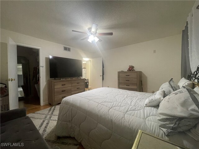 bedroom with a textured ceiling, light wood-type flooring, and ceiling fan