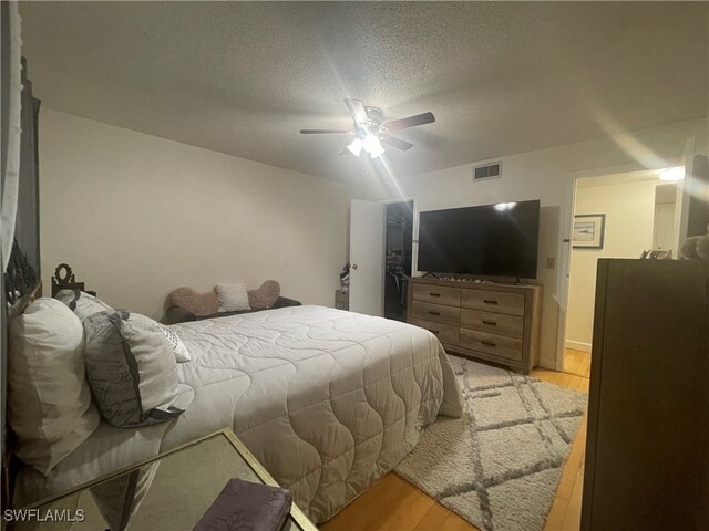 bedroom featuring ceiling fan, a textured ceiling, and light hardwood / wood-style floors