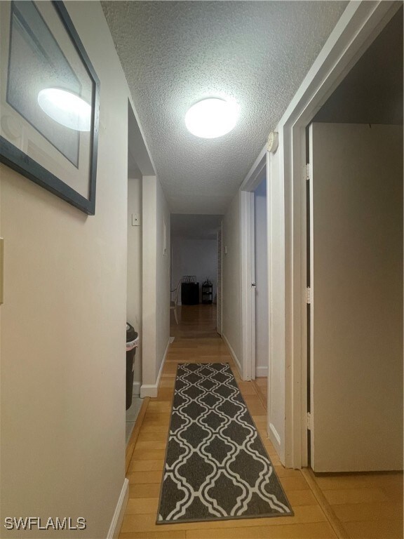 hallway with light hardwood / wood-style floors and a textured ceiling