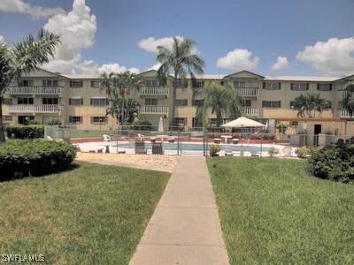 view of property's community featuring a lawn and a swimming pool