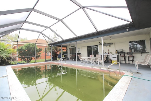 view of swimming pool featuring ceiling fan, a lanai, an outdoor bar, and a patio area