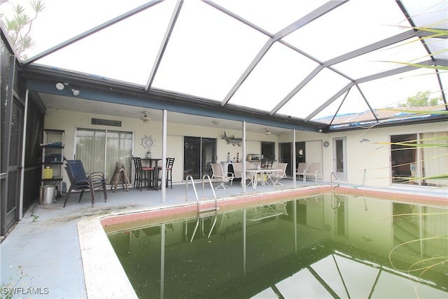 view of pool with glass enclosure, ceiling fan, and a patio area