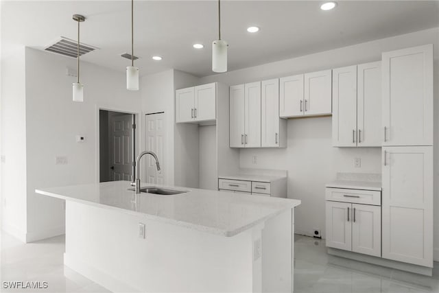 kitchen with sink, white cabinetry, an island with sink, and hanging light fixtures