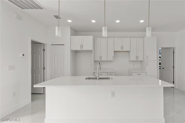 kitchen featuring white cabinetry, a kitchen island with sink, and hanging light fixtures