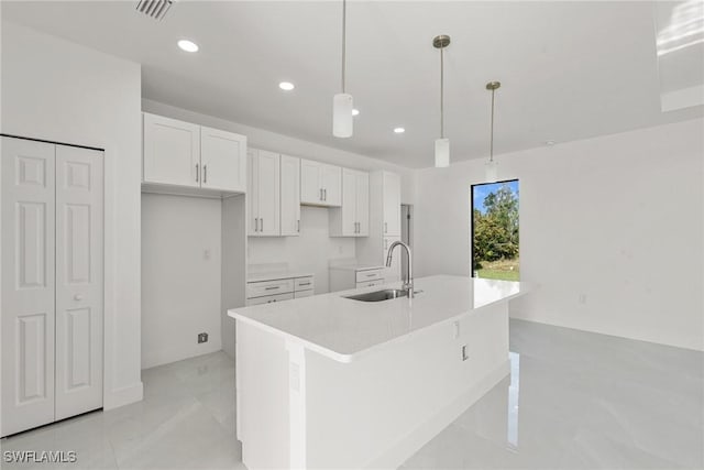 kitchen with white cabinetry, an island with sink, and hanging light fixtures