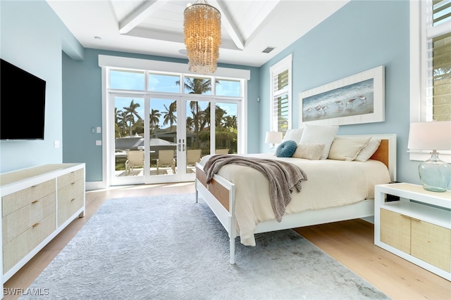 bedroom with access to outside, hardwood / wood-style floors, a raised ceiling, and a notable chandelier