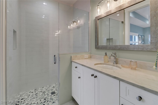 bathroom featuring a shower with door and vanity