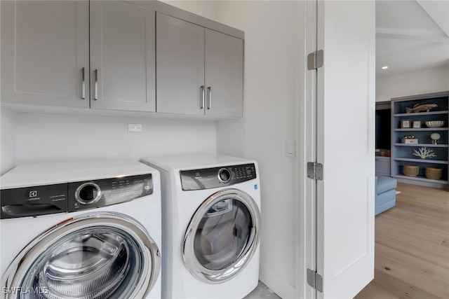 laundry room with light wood-type flooring, cabinets, and washer and dryer