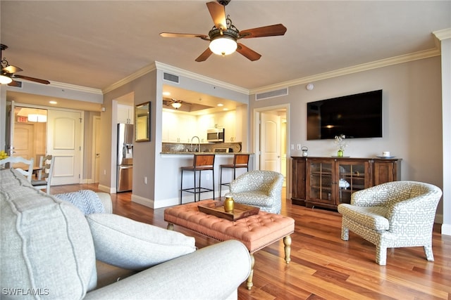 living room with light hardwood / wood-style flooring, ceiling fan, ornamental molding, and sink