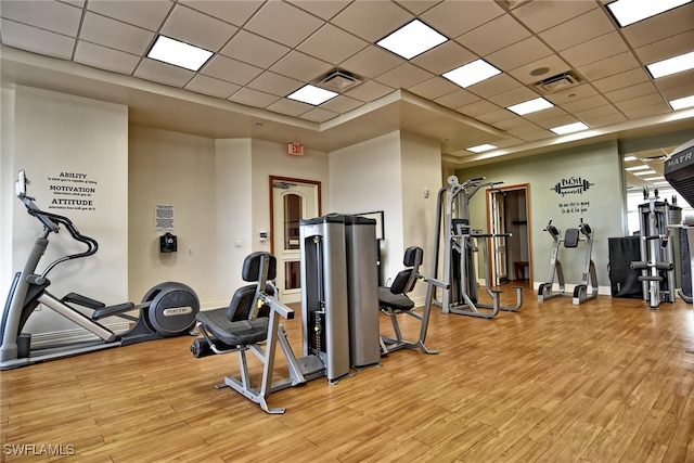 exercise room featuring light hardwood / wood-style floors and a drop ceiling