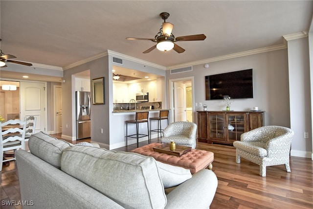 living room featuring hardwood / wood-style flooring, ceiling fan, and ornamental molding