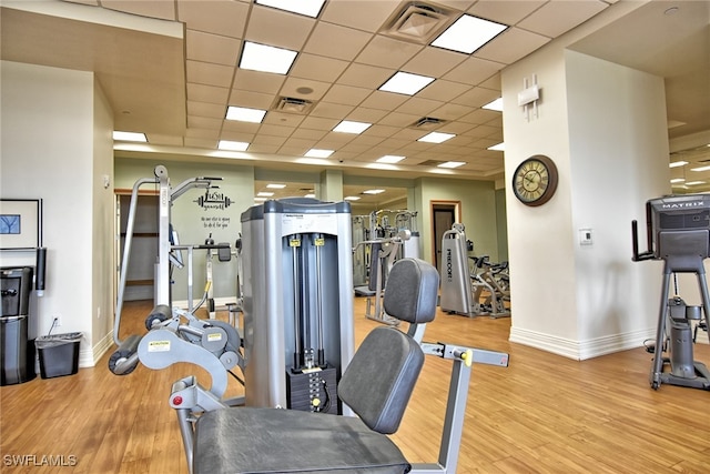 gym featuring a drop ceiling and light wood-type flooring