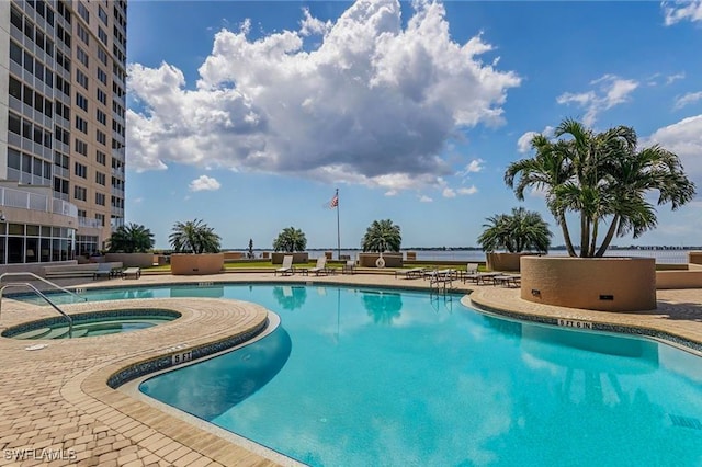 view of swimming pool featuring a water view, a patio, and a hot tub