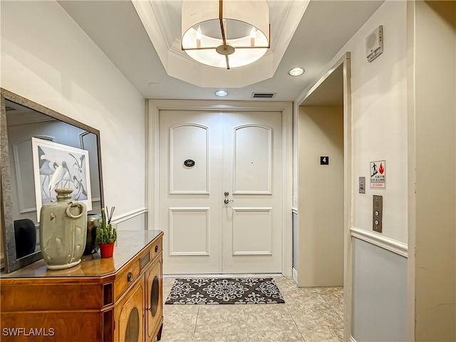 doorway to outside featuring a tray ceiling, an inviting chandelier, crown molding, and light tile patterned flooring