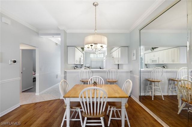 dining space with light hardwood / wood-style floors and ornamental molding