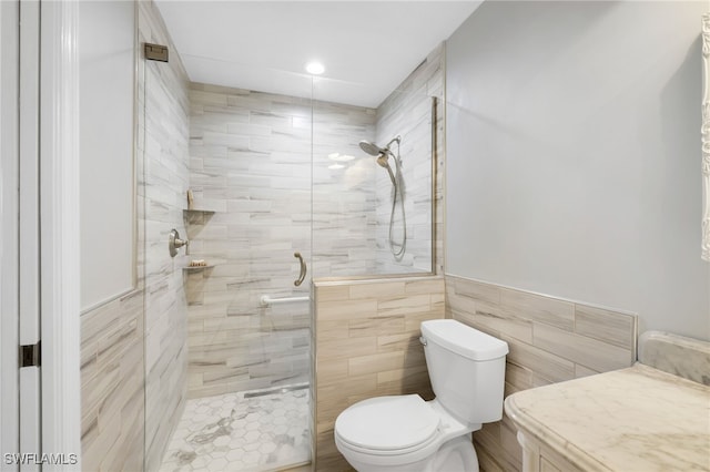 bathroom with vanity, toilet, tile walls, and tiled shower