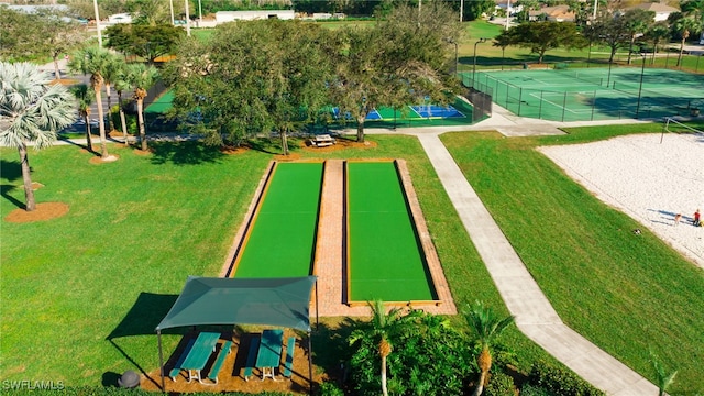 surrounding community featuring tennis court and a lawn