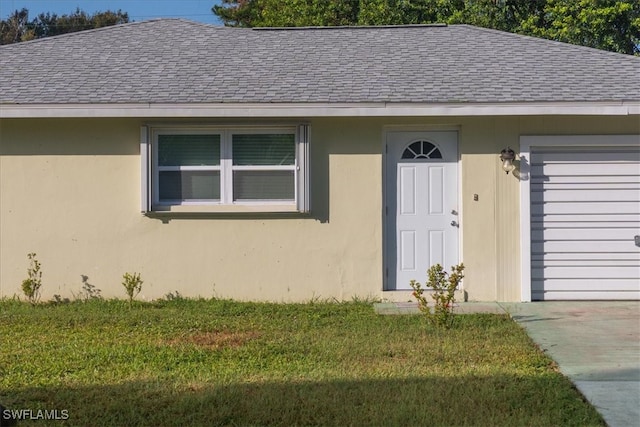 property entrance featuring a garage and a yard