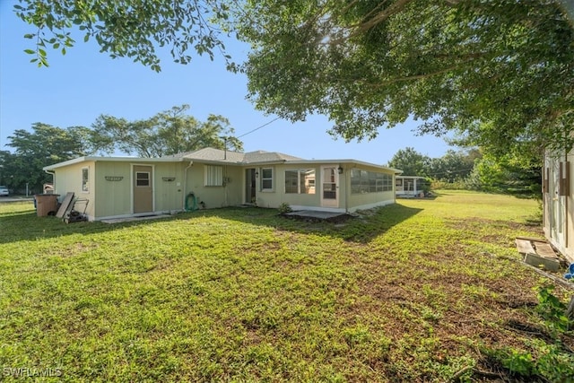 rear view of property with a lawn and a sunroom