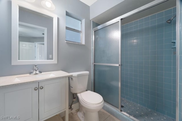 bathroom featuring toilet, tile patterned floors, vanity, and a shower with door