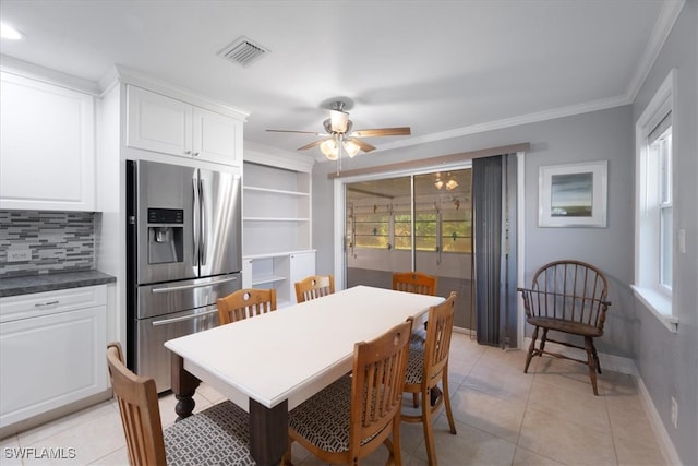 tiled dining space with ceiling fan and crown molding