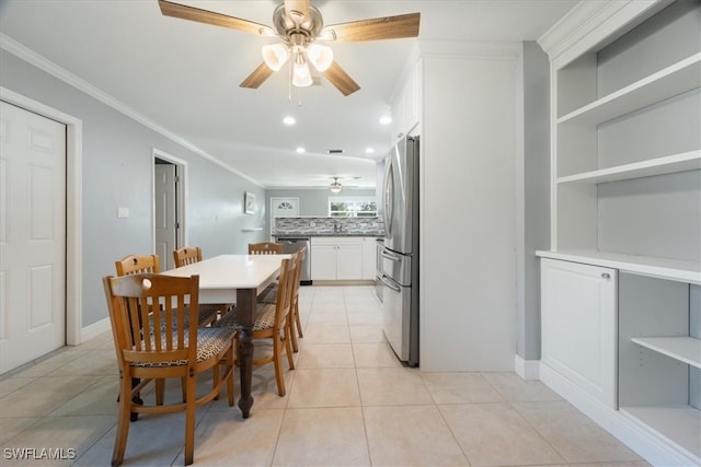 tiled dining space featuring ceiling fan, crown molding, and sink