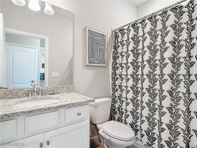 bathroom with curtained shower, vanity, and toilet