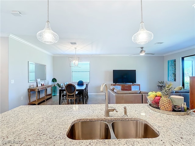 kitchen with ornamental molding, sink, ceiling fan, and light stone countertops