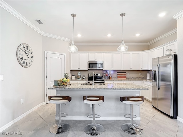 kitchen with stainless steel appliances, hanging light fixtures, sink, white cabinets, and a kitchen island with sink