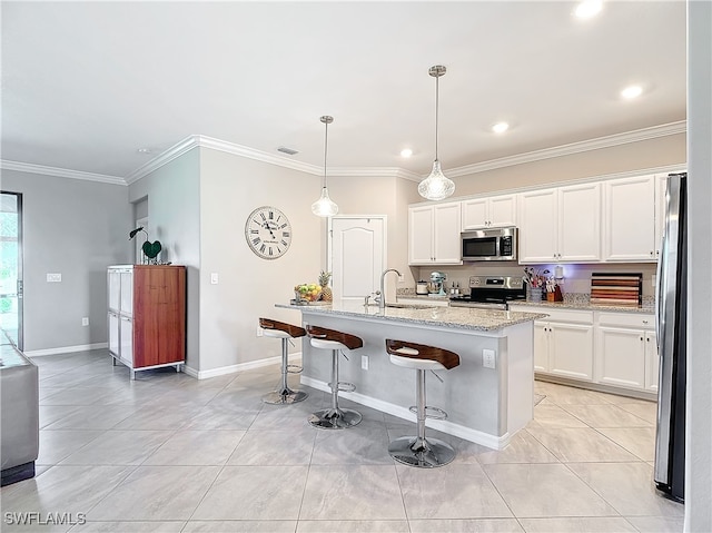 kitchen with stainless steel appliances, a center island with sink, pendant lighting, and white cabinetry